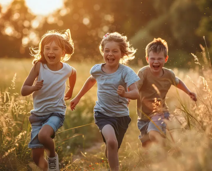 3 Kinder laufen auf einer Wiese